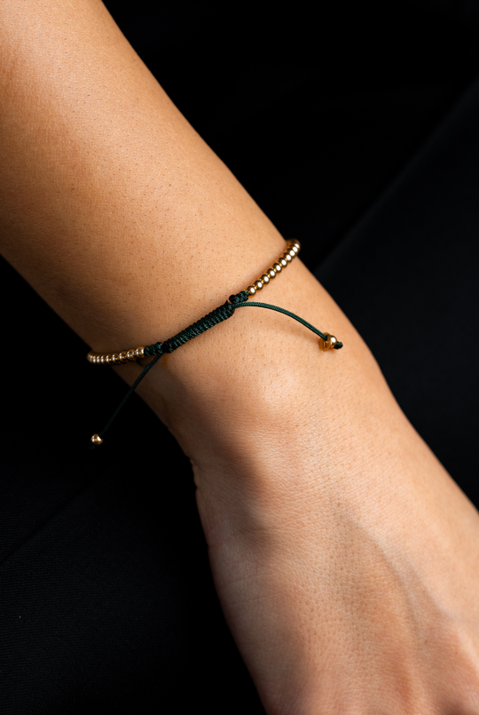 Pulseira em algodão verde escuro com bolinhas douradas.